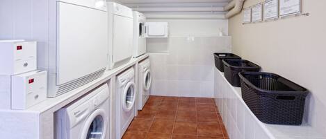 A laundry room with a front-loading washer and dryer, a microwave, and baskets for laundry.