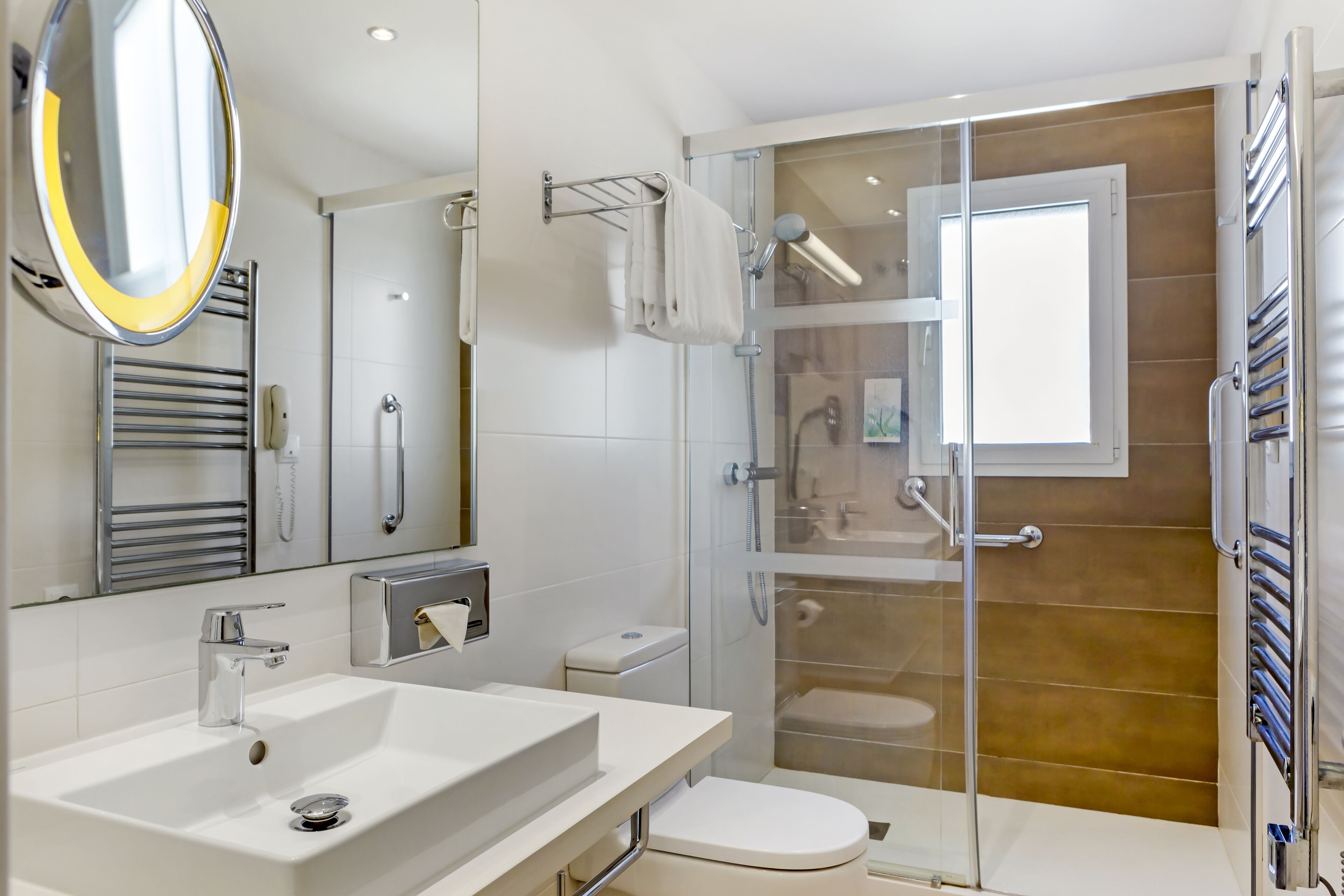 Un baño moderno con ducha de vidrio, lavamanos blanco y retrete.