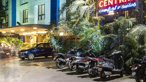 En parkeringsplats med flera motorcyklar och en bil, en byggnad med en skylt som visar texten ”Park Central”, och några palmer.