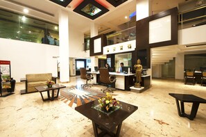 Eine großzügige Lobby mit Empfangsschalter, Sitzgelegenheiten und einer Statue.