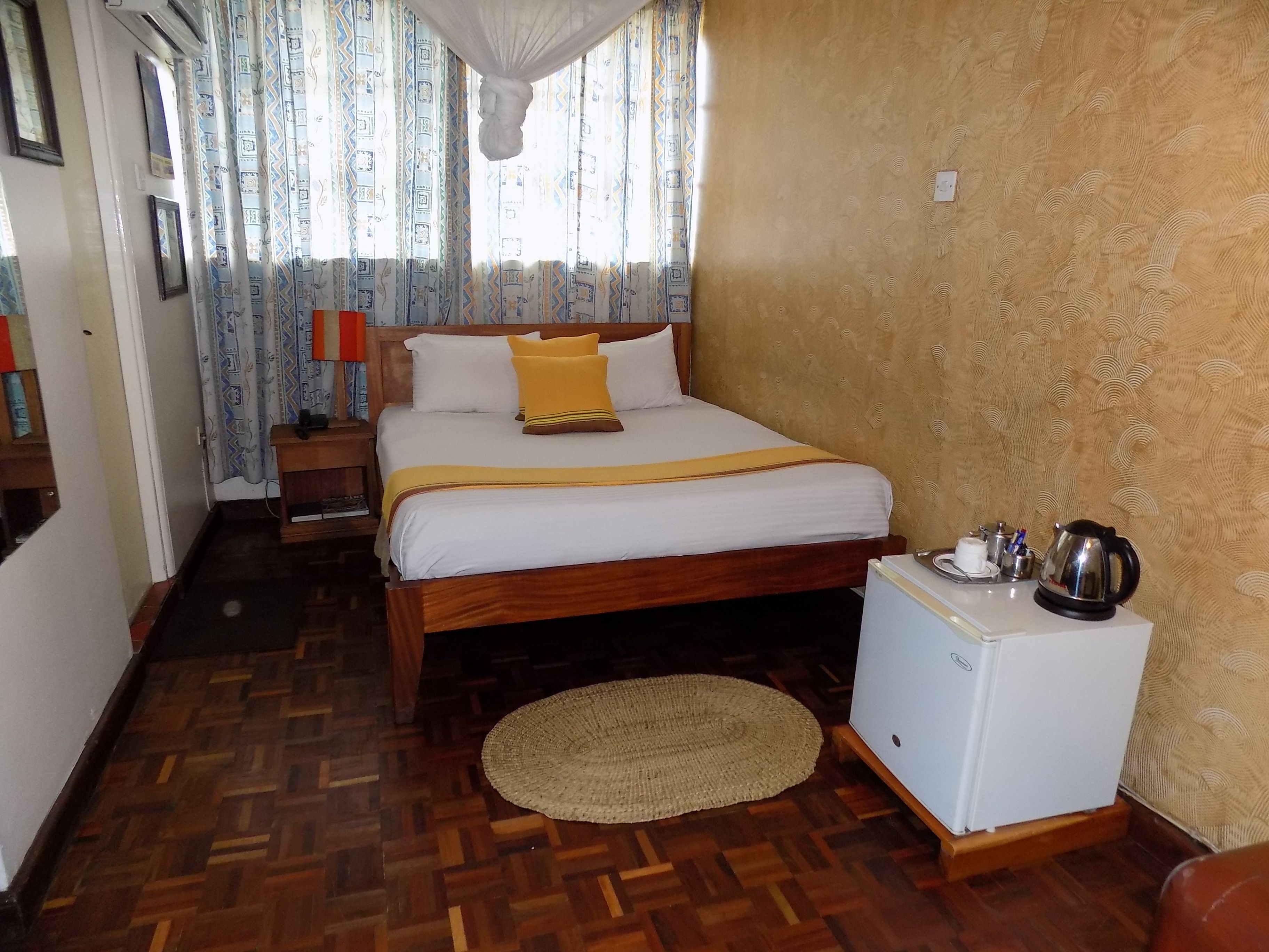 A neatly arranged bedroom with a bed, bedside table, and a small refrigerator.