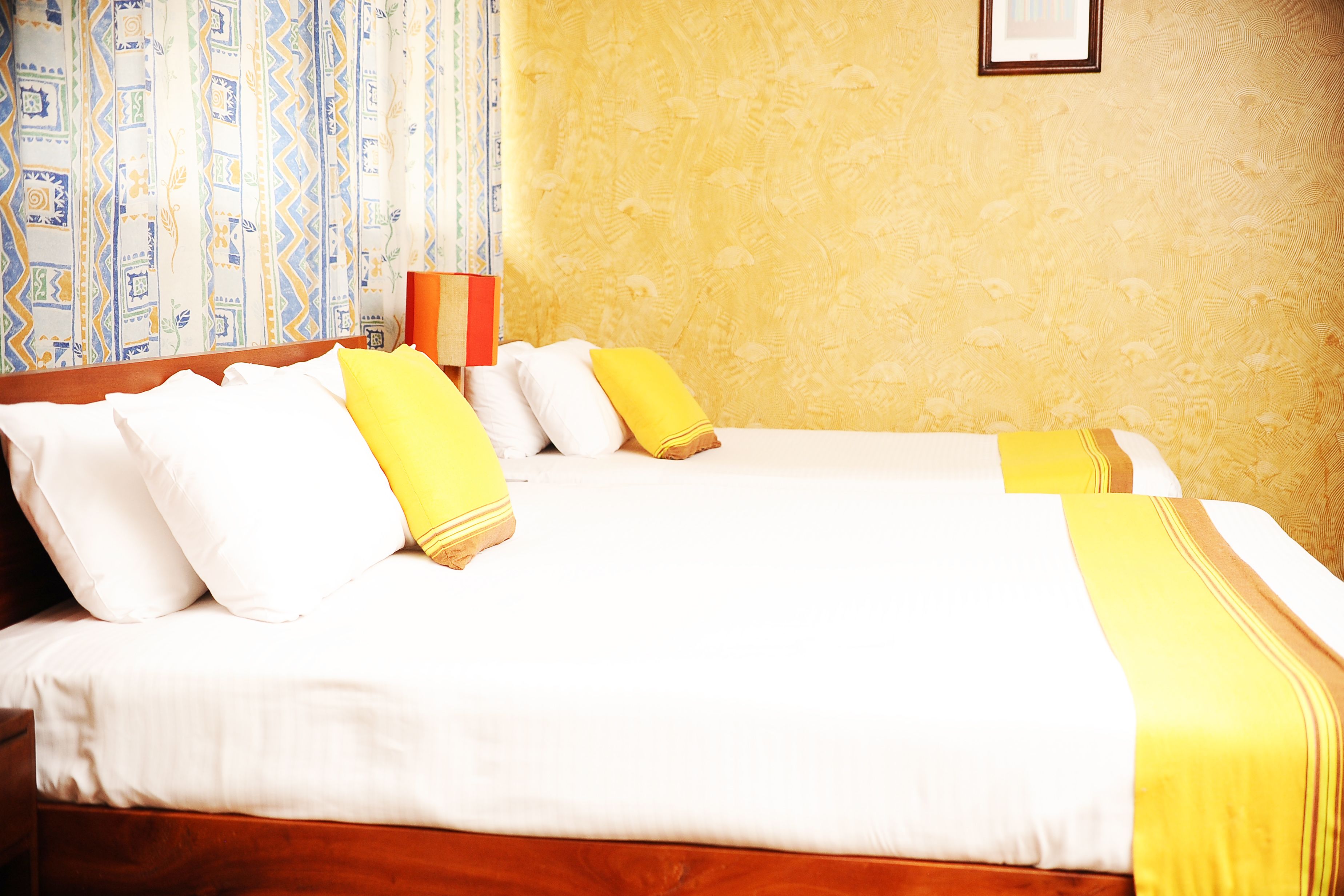 Ein Hotelzimmer mit zwei Betten, weißer Bettwäsche und gelben Akzenten.