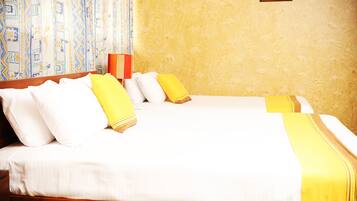 Quarto de hotel com duas camas, roupa de cama branca e detalhes em amarelo.