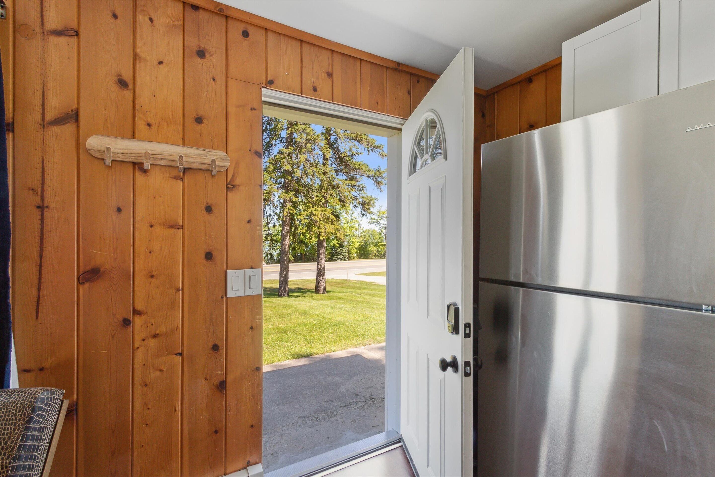 Una cocina con refrigerador de acero inoxidable, paredes de madera y una puerta que da al exterior.