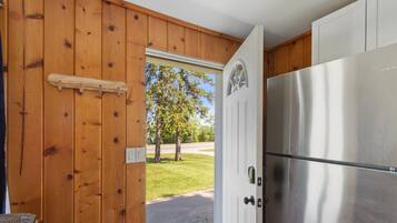 Una cocina con refrigerador de acero inoxidable, paredes de madera y una puerta que da al exterior.