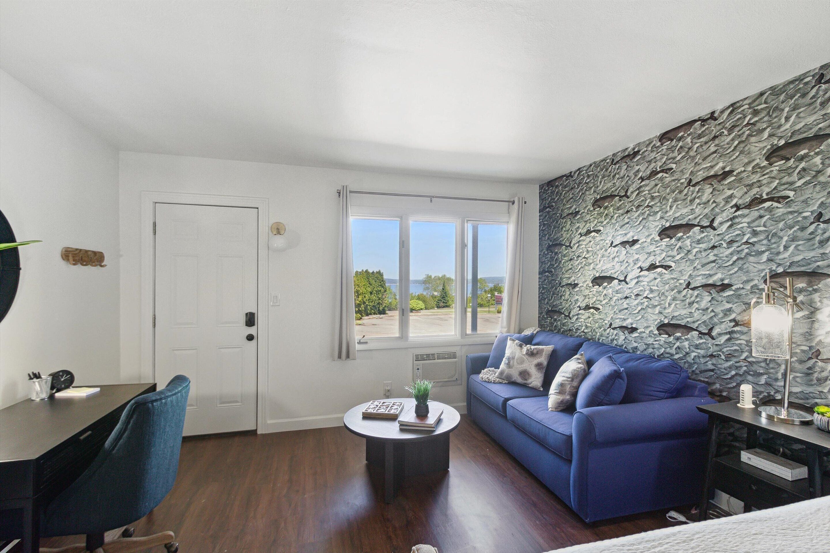 A modern living room with a blue sofa, a round coffee table, and a stone wall.