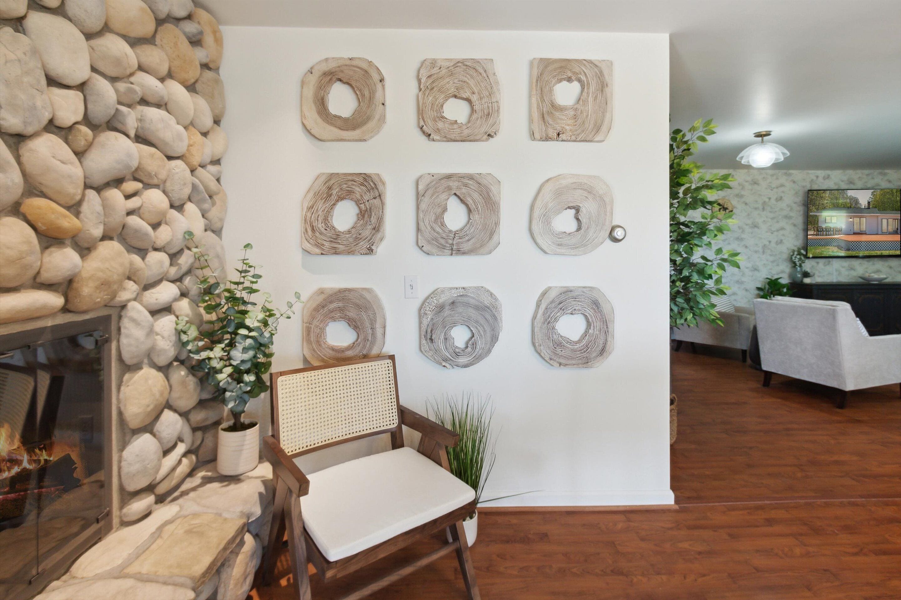 Una habitación con chimenea de piedra, una silla de madera y una pared decorada con piezas de madera circulares.