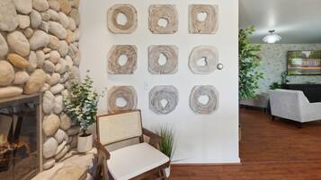 Una habitación con chimenea de piedra, una silla de madera y una pared decorada con piezas de madera circulares.