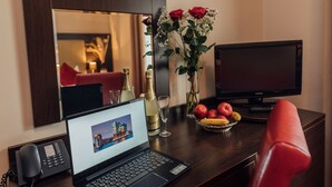 Ein Hotelzimmer mit Schreibtisch, Laptop, Telefon und Fernseher.