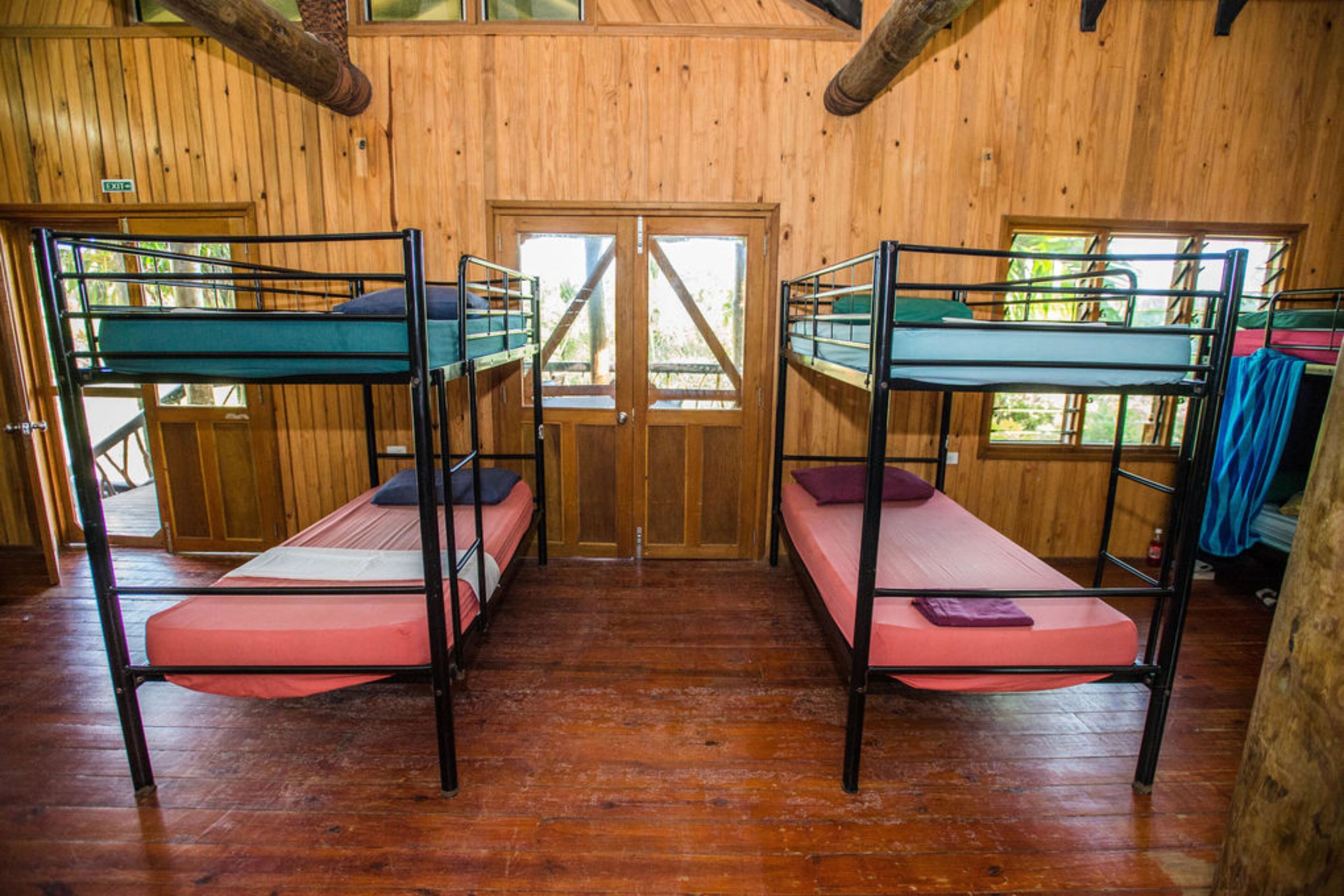A room with two bunk beds, wooden walls, and a wooden floor.