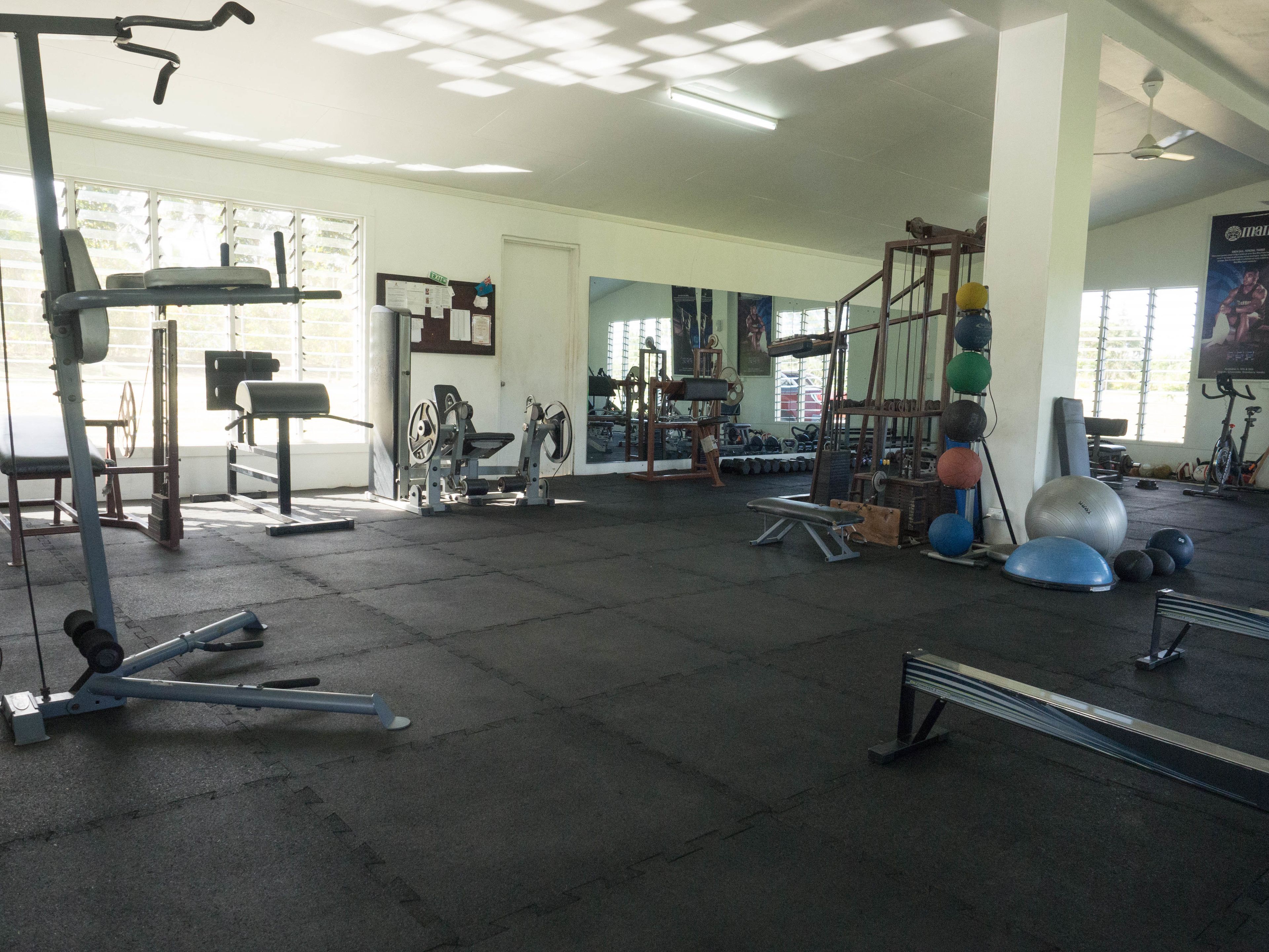 A gym with various exercise equipment, large windows, and a ceiling fan.