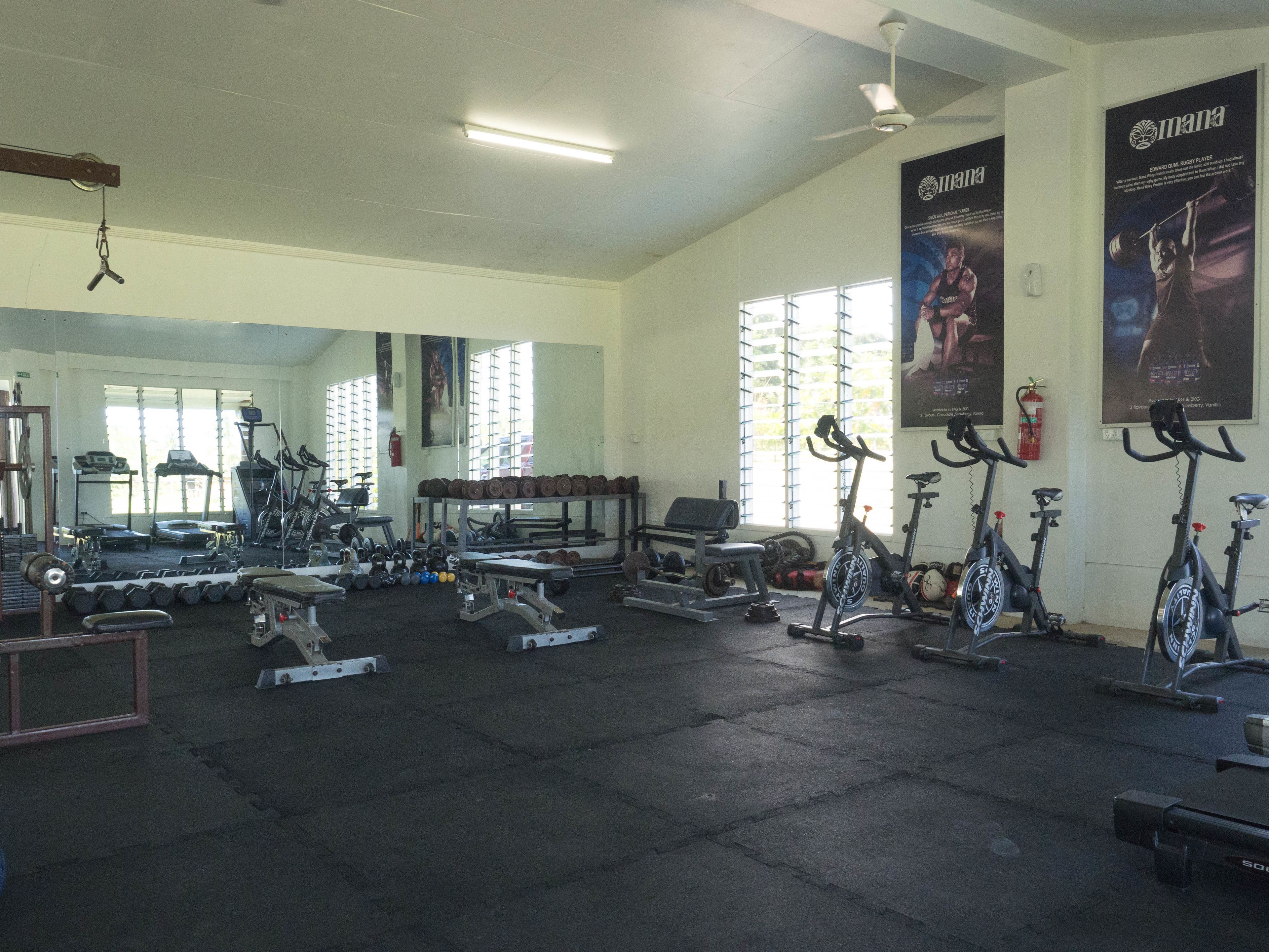 Un gimnasio con varios equipos de ejercicio, incluyendo cintas de correr, bicicletas estáticas y pesas libres.
