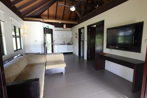 Un espacio de estar moderno con un sofá, un televisor de pantalla plana y una cocina al fondo.