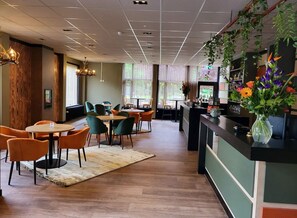 Un hall d’hôtel comprenant un comptoir d’accueil, un espace salon et une grande fenêtre.