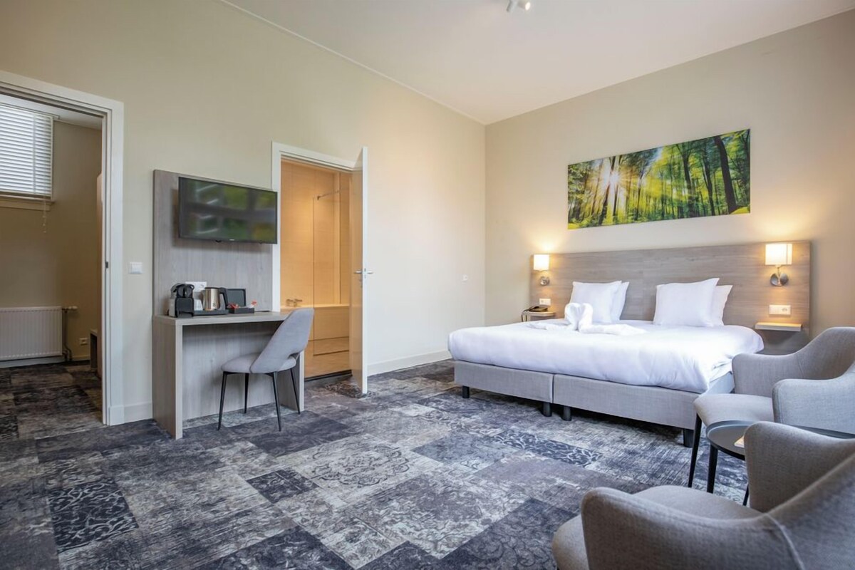 Une chambre d’hôtel avec un lit, un bureau, une chaise et un tableau au mur.