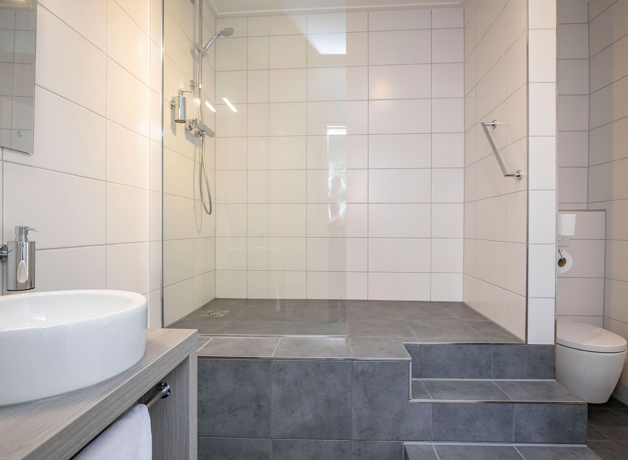 Un baño moderno con ducha, inodoro y lavamanos.