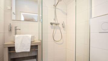 Ein modernes Badezimmer mit einer Duschkabine aus Glas, einem Holzwaschtisch und einer weißen Toilette.