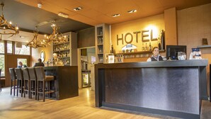 Un hall d’accueil d’hôtel avec un bar, des sièges et un lustre.