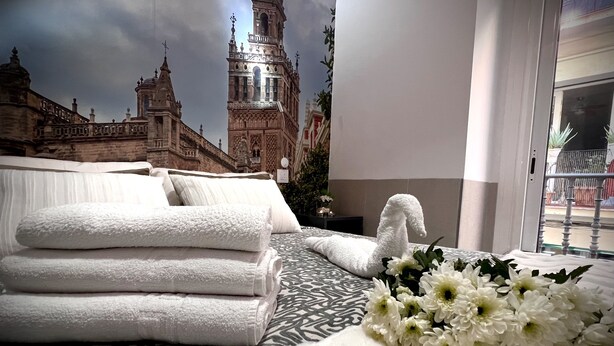 A hotel room with a bed, white towels, and a bouquet of flowers. - Hostal Paco's (Seville)