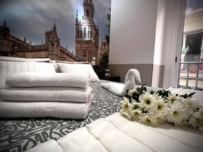 Habitación de hotel con una cama, toallas blancas y un ramo de flores.