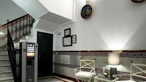 A spacious lobby with a marble floor, a staircase, and a reception area with a counter and chairs. - Hostal Paco's (Seville)