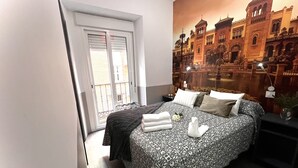A bedroom with a bed, a nightstand, a lamp, and a window with blinds. - Hostal Paco's (Seville)