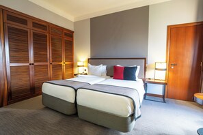 A hotel room with a large bed, a wardrobe, a bedside table with a lamp, and a door. - Hotel Dighton (Oliveira De Azemeis)