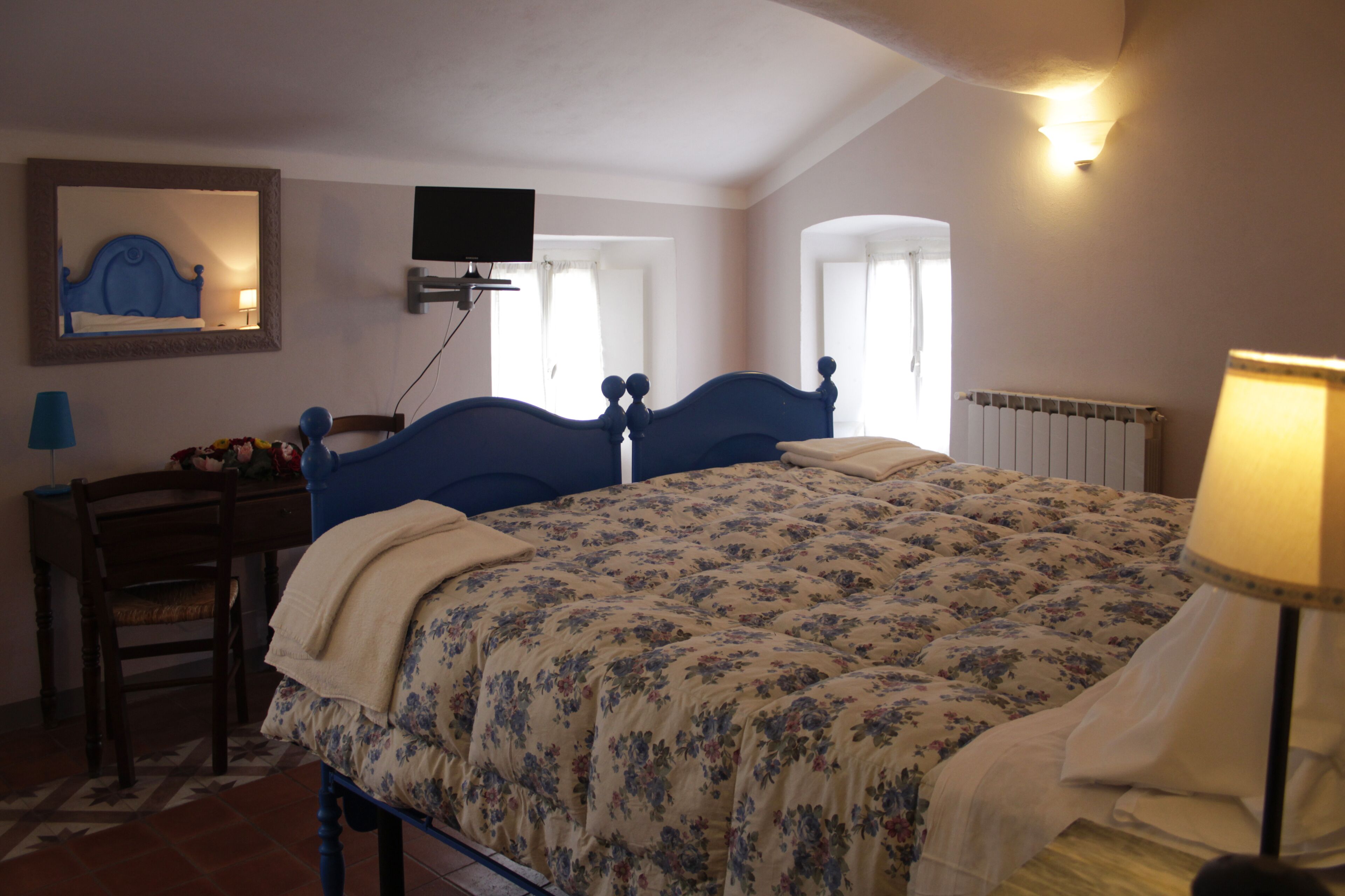 Un dormitorio con cama, escritorio, silla, televisor y ventana.