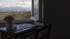 Een kamer met uitzicht op een bergachtig landschap door een raam.
