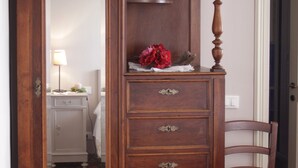 Een houten dressoir met spiegel, lades en een klein plankje met een rode bloem.