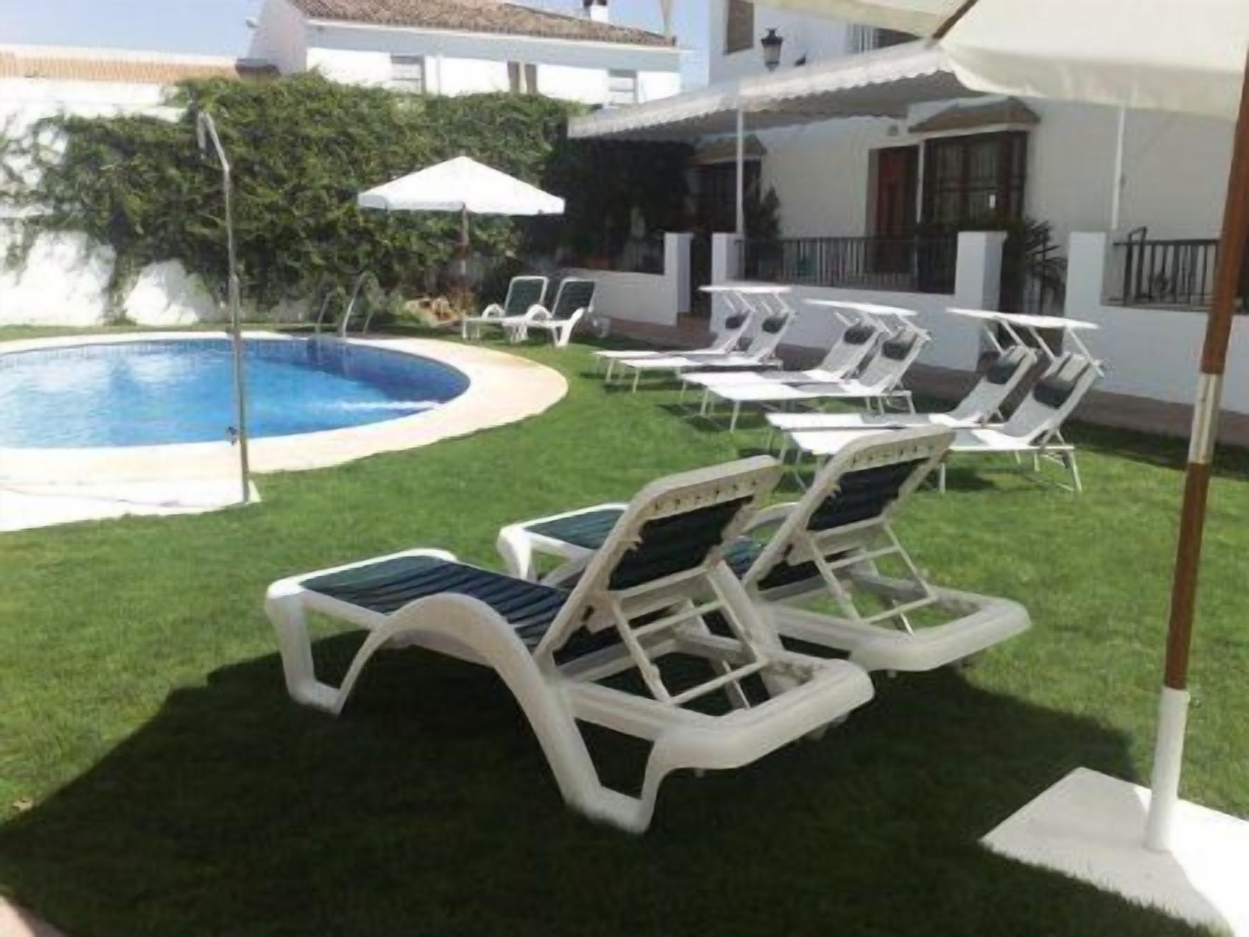 Un área junto a la piscina con sillones de descanso y sombrillas.