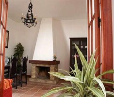 Una habitación con chimenea, candelabro y planta en maceta.