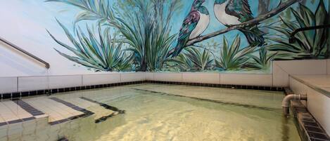 Una piscina con un mural de pájaros en la pared.