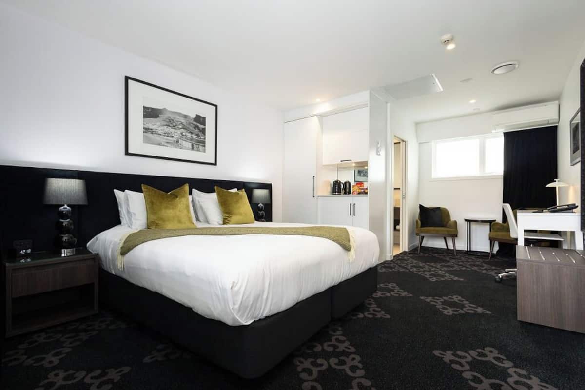 A modern hotel room with a large bed, a desk, and a chair.