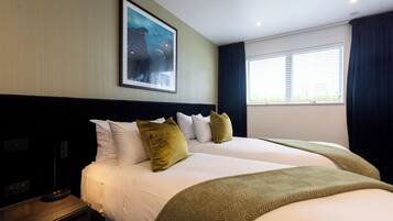 A hotel room with a large bed, a nightstand, a lamp, and a painting on the wall.
