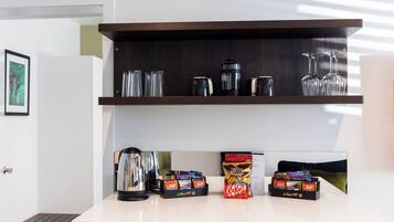 En köksbänk med en kaffebryggare, glas och behållare för snacks.