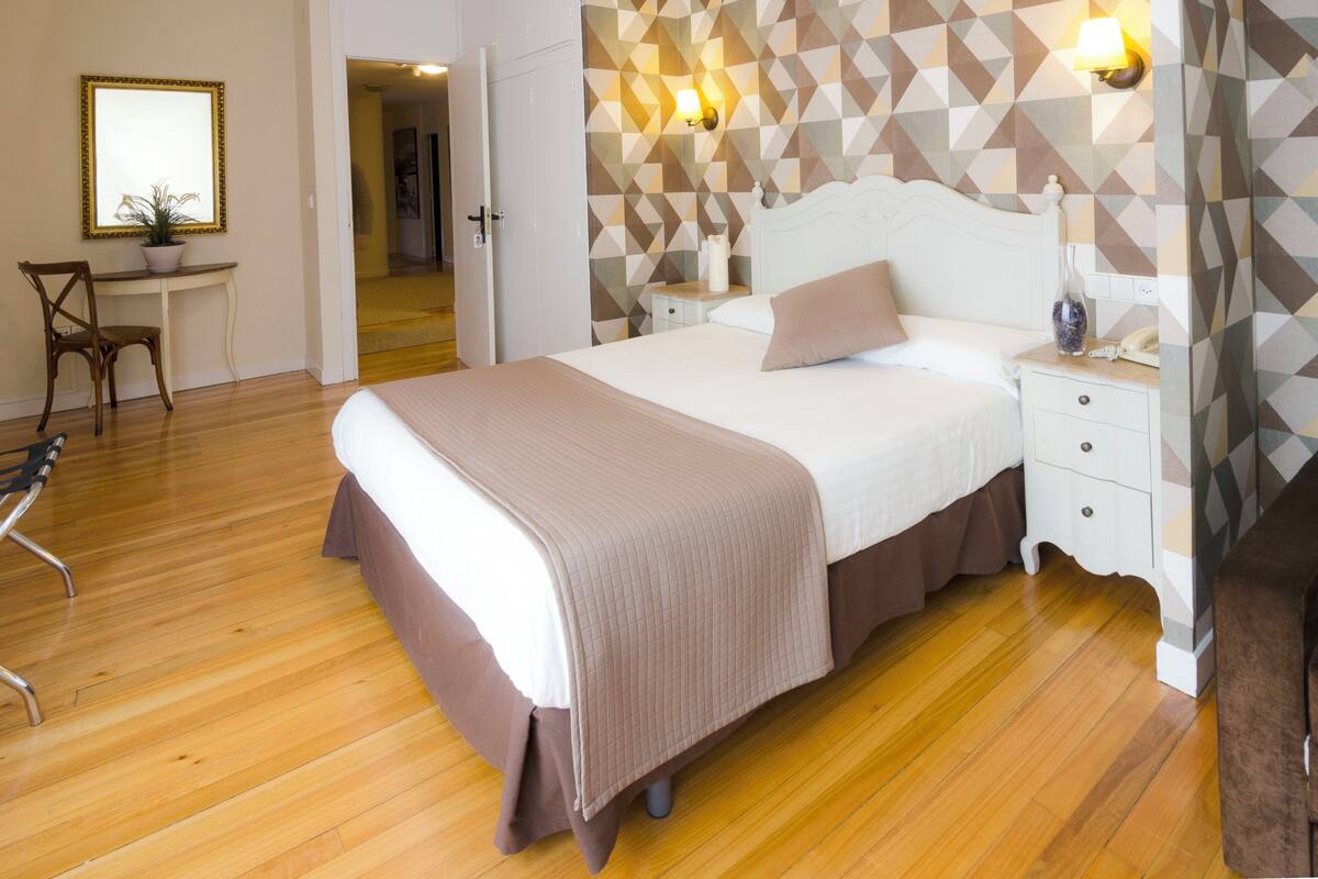 A neatly arranged bedroom with a bed, bedside tables, a chair, and a desk.