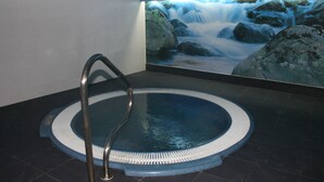 A spa area with a hot tub, a stone wall, and a waterfall mural. - Hotel & Spa Arha Potes (Potes)
