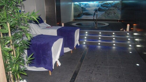 A spa room with two massage tables, a hot tub, and a waterfall mural on the wall. - Hotel & Spa Arha Potes (Potes)