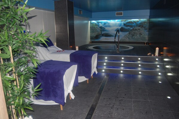 A spa room with two massage tables, a hot tub, and a waterfall mural on the wall. - Hotel & Spa Arha Potes (Potes)
