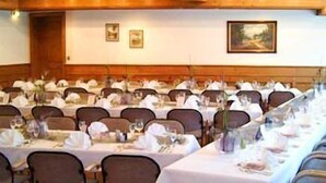 Un salón de conferencias con filas de mesas y sillas, manteles blancos y cuadros en las paredes.