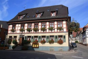 A traditional half-timbered building with a steep gabled roof, multiple windows with shutters, and flower boxes on the ground floor. - Landgasthof & Hotel Krone (Konigsbach-Stein)