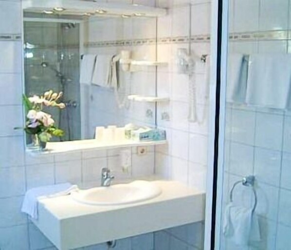 A bathroom with a white sink, a mirror, and a glass shower enclosure. - Landgasthof & Hotel Krone (Konigsbach-Stein)