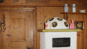 Una cocina rústica con una puerta de madera, una estufa con detalles decorativos y un banco con cojines.