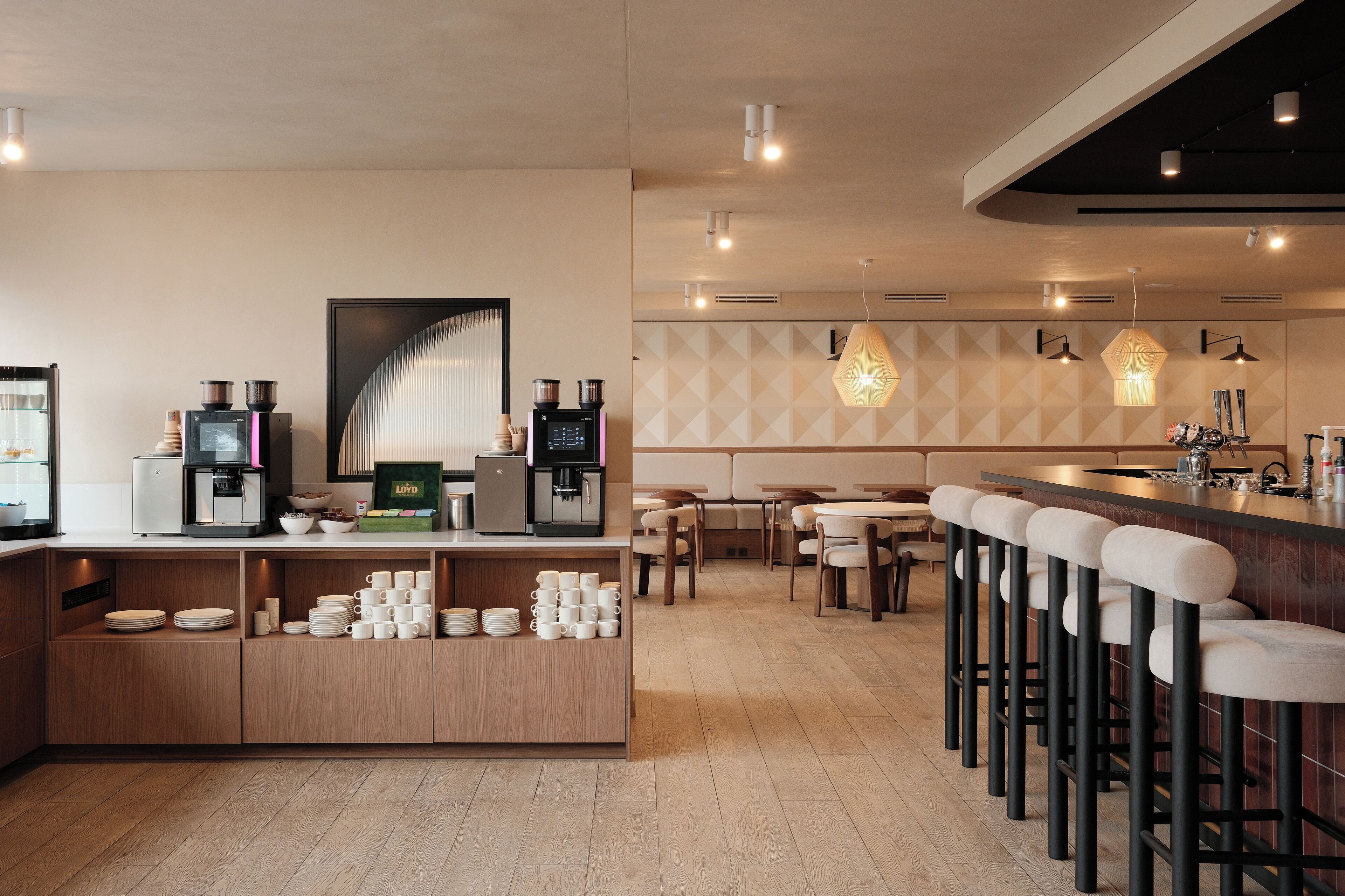 A modern cafe with a bar area, seating, and a coffee machine.