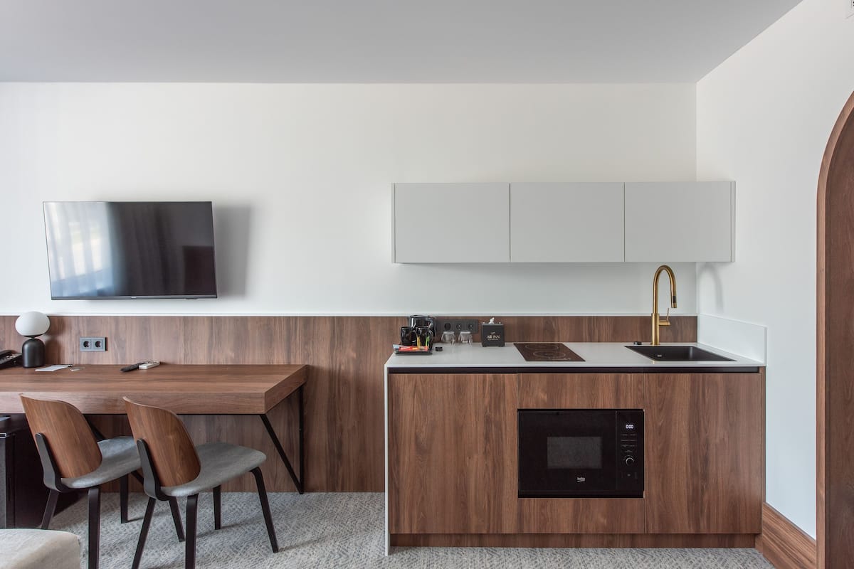 A compact kitchen with a built-in oven, a sink, and a flat-screen TV mounted above the counter.