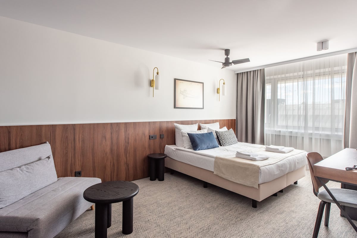 A hotel room with a bed, a sofa, a small table, and a chair.