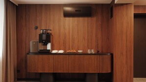 Una kitchenette moderna con una cafetera integrada, una pequeña encimera y un armario debajo.