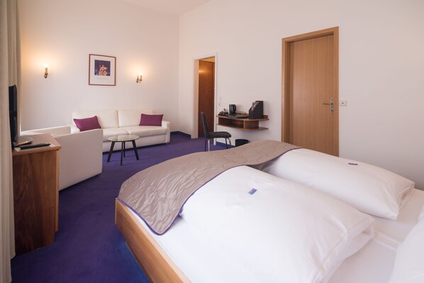 A hotel room with a bed, a sofa, a desk, a chair, a coffee machine, and a door. - Hotel Etol (Baden-Baden)