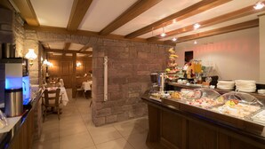 Un área de bufé con pared de piedra, vigas de madera en el techo y diversas opciones de comida.